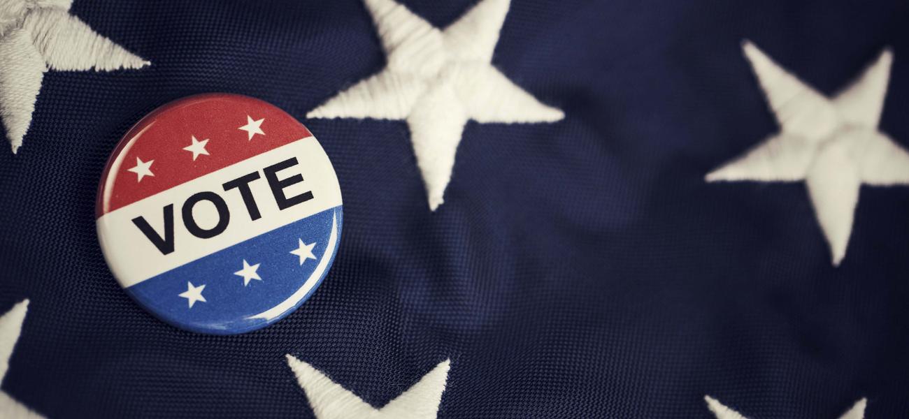 Vote pin on an American flag.