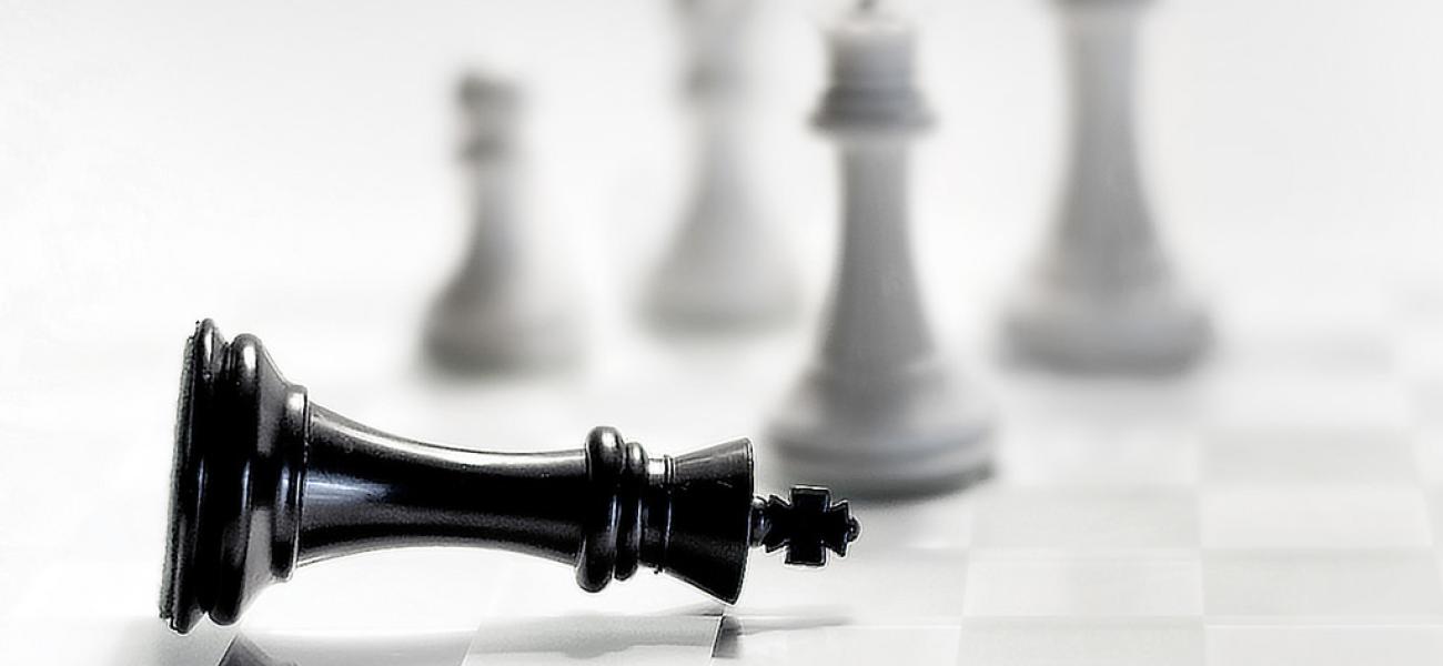 White chess pieces standing up near fallen black piece.
