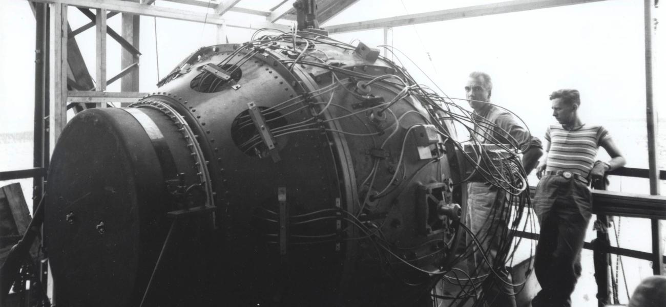 Norris Bradbury and Boyce McDaniel stand with Trinity nuclear device at Los Alamos National Laboratory.