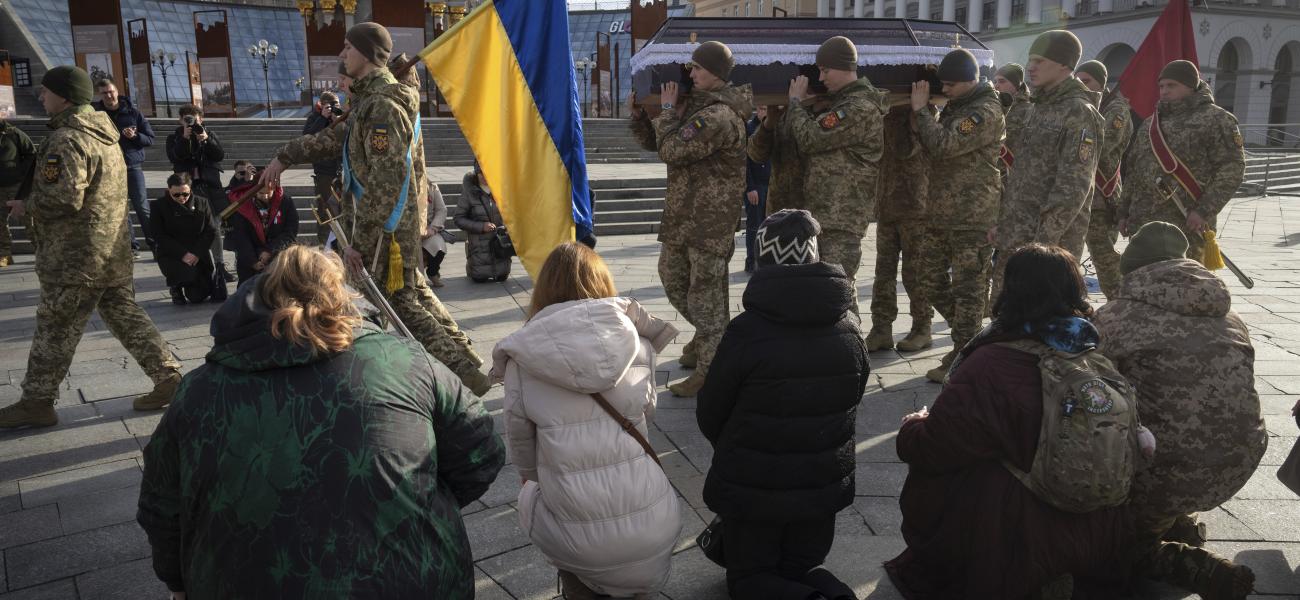 People kneel as soldiers carry a coffin of Poland's volunteer soldier, Filip Antosiak, 18, who served in the 25th separate airborne brigade of the Armed Forces of Ukraine and was killed in the Russia-Ukraine war, during funeral ceremony in the Independence square in Kyiv, Ukraine, Thursday, Jan. 30, 2025. (AP Photo/Efrem Lukatsky)
