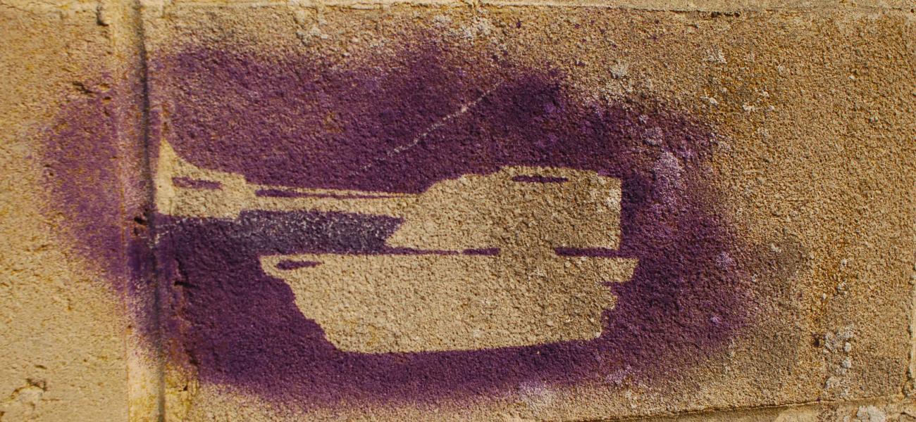 Tank silhouette spray-painted on a brick wall.