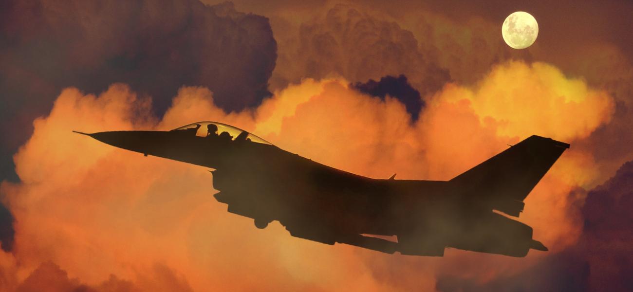 Fighter jet among orange clouds.