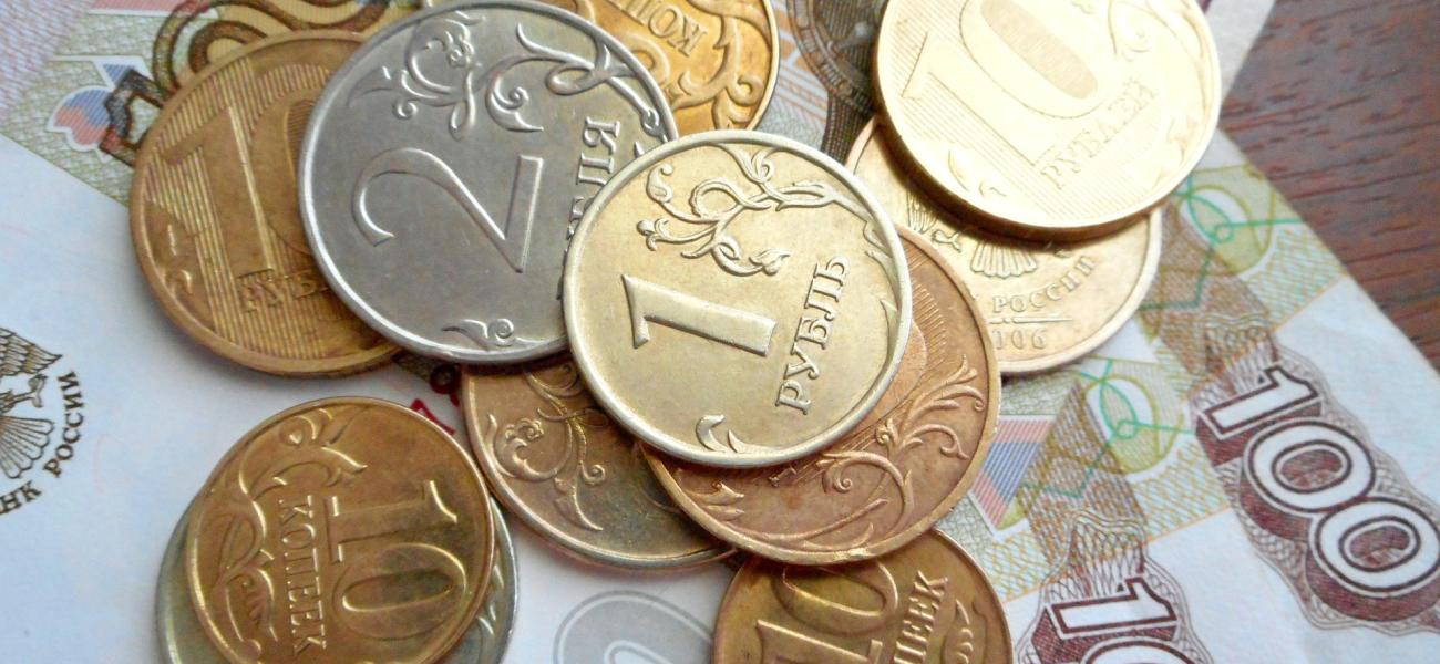 Russian ruble coins on top of Russian ruble bills. 