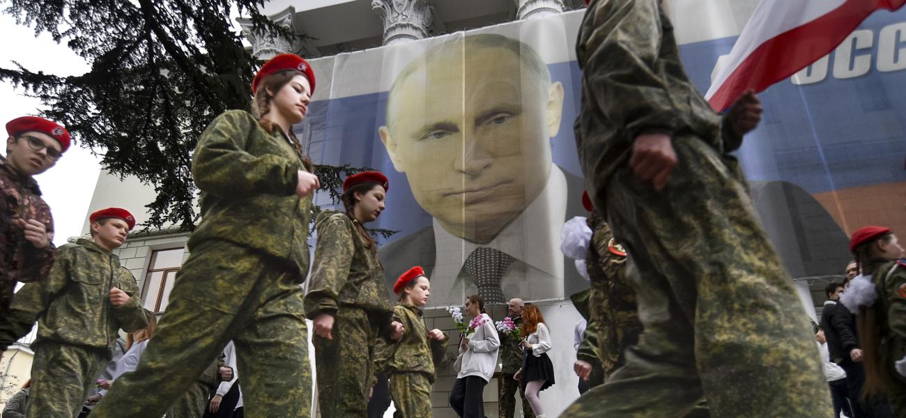 Youths mark the ninth anniversary of the annexation of Crimea from Ukraine with a banner reading, "Russia doesn't start wars, it ends them," next to an image of Russian President Vladimir Putin in Yalta, Crimea, on March 17, 2023. (AP Photo, File)