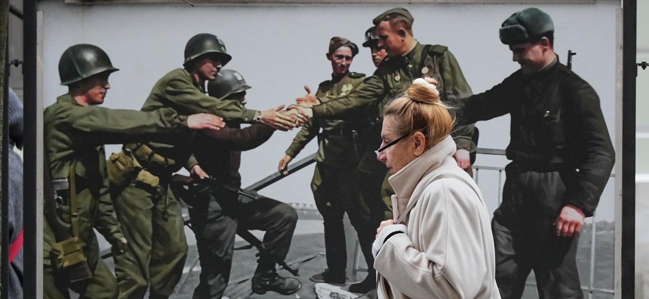 A woman walks past an image of American, left, and Soviet troops meeting on April 25, 1945 at the Elbe River in Germany during World War II at a street exhibition of colorised photos dedicated for the recent celebration of the end of World War II, in St. Petersburg, Russia, Friday, Nov. 21, 2025. (AP Photo/Dmitri Lovetsky)